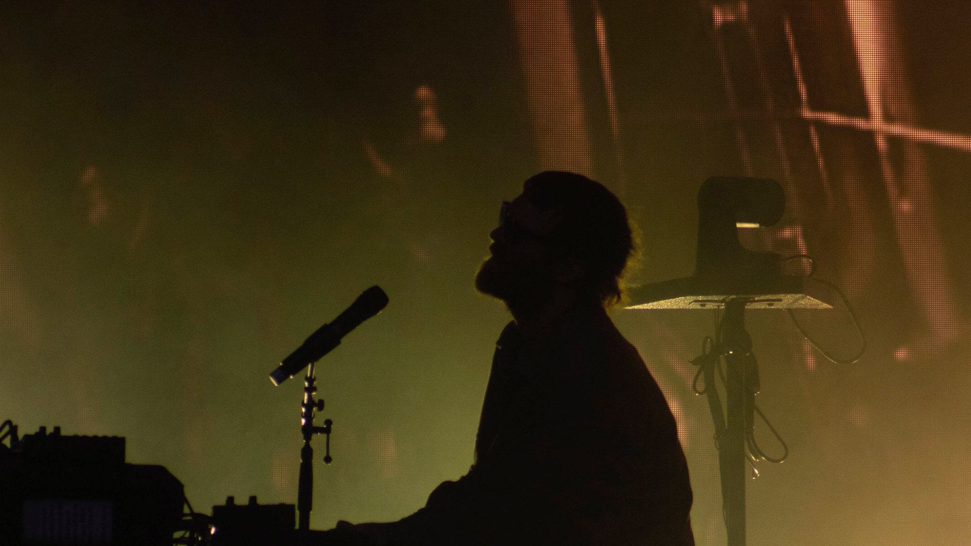 A musician in silhouette on stage, under the lights from above