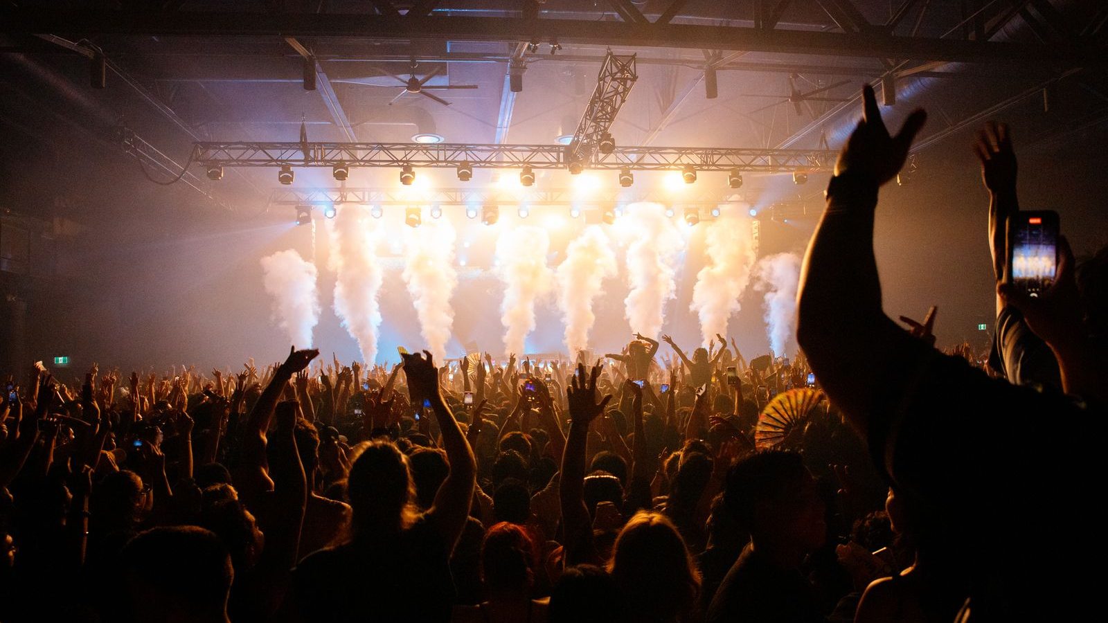 A crowd in a packed room, lit from the stage